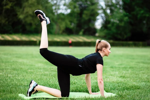 Sağlıklı spor yaşam tarzı. Spor elbiseli genç bir kadın spor egzersizleri yapıyor. Stadyumdaki fitness kadını. Genç kadın çömeliyor. Genç kız spor için içeri giriyor. Fitness Sporu. Esniyorum.