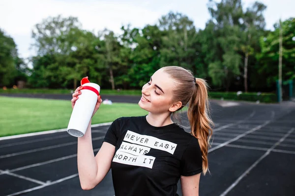 健身健美的女运动员一大早在体育场跑步 健康的生活方式理念 年轻女人喝瓶子里的水 早上跑 训练后的运动员 青年妇女与体育 — 图库照片