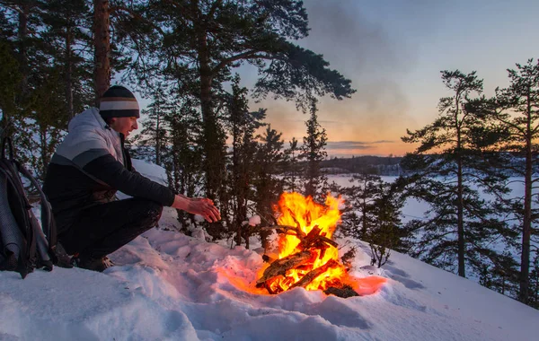 ateşin yanında karlı bir dağ başında oturan turist. Karelya. Ladoga Gölü. Rusya