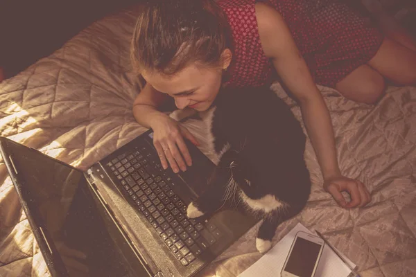 girl with black cat working on the computer