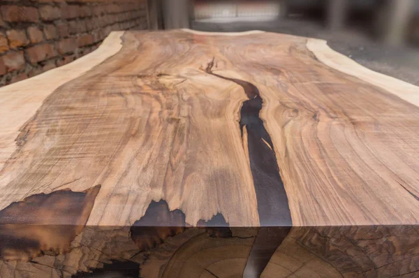 Katı cevizden yapılmış ahşap bir masa tuğla bir duvarın arkasında epoksi reçine var.