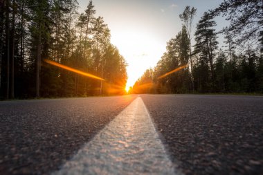 Batan güneşin arka planında asfalt yol