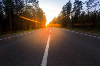 Batan güneşin arka planında asfalt yol