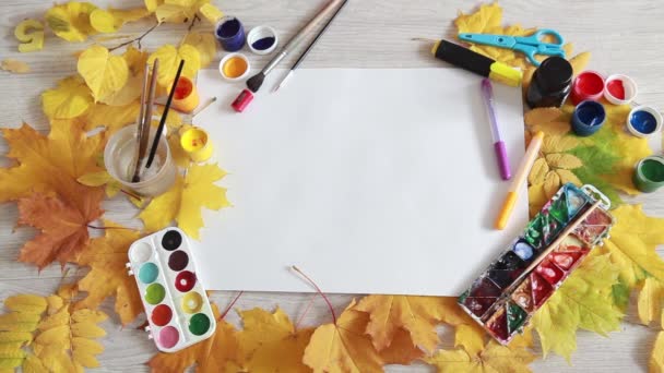Художник расставляет предметы для творчества на столе с осенними листьями . — стоковое видео