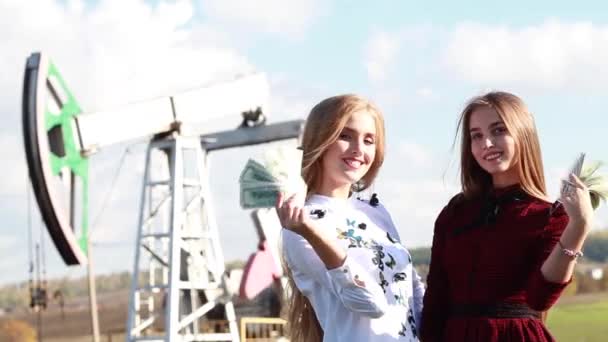 Two young women converted dollars into oil fields. Income from oil — Stock Video