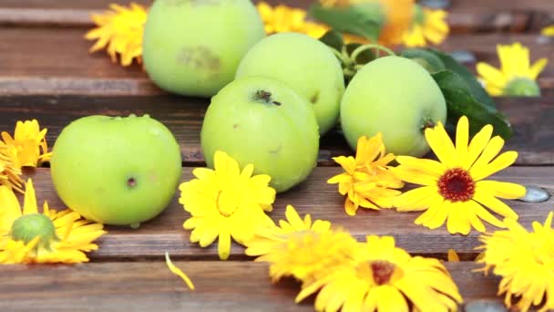 Вінтажні зелені яблука і помаранчеві квіти цвяхи на дерев'яній поверхні літній день на відкритому повітрі в саду — стокове відео