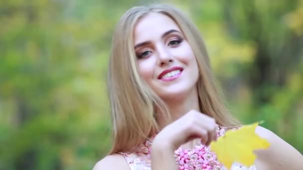 Hermosa mujer cubre su cara con hojas de arce amarillo en el día de otoño en el parque — Vídeos de Stock