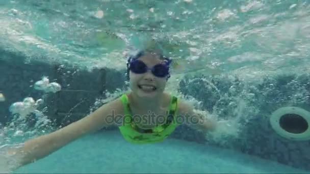 Barnet simmar under vattnet i poolen — Stockvideo