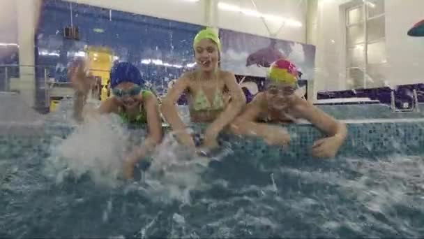 Divertidos niños se divierten en la piscina con chorros de agua — Vídeo de stock