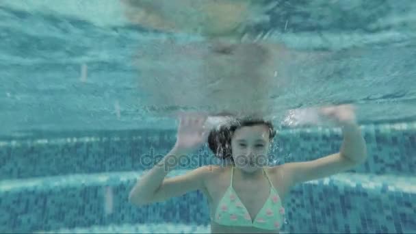 Adolescente bajo el agua en la piscina flota saludando — Vídeo de stock