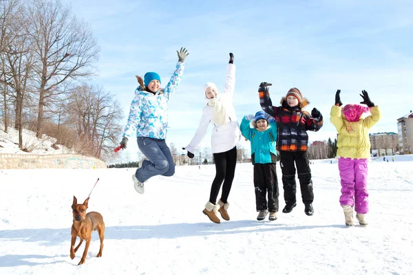 Šťastná rodina se psem v skok na zimní procházka — Stock fotografie