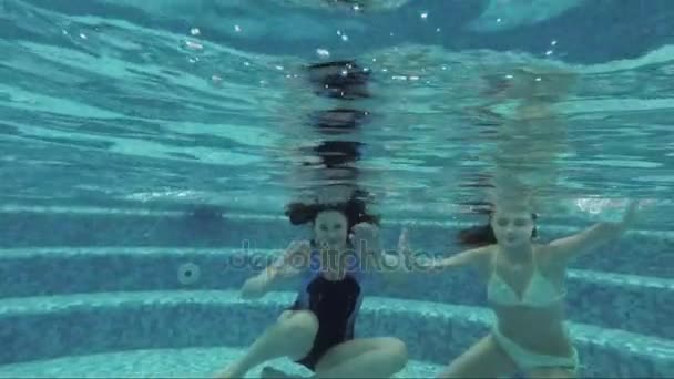 Uma mulher e uma menina nadando debaixo d 'água na piscina — Vídeo de Stock