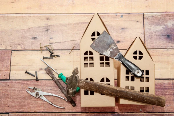 Decorative cardboard houses and repair tools on a wooden background — Stock Photo, Image