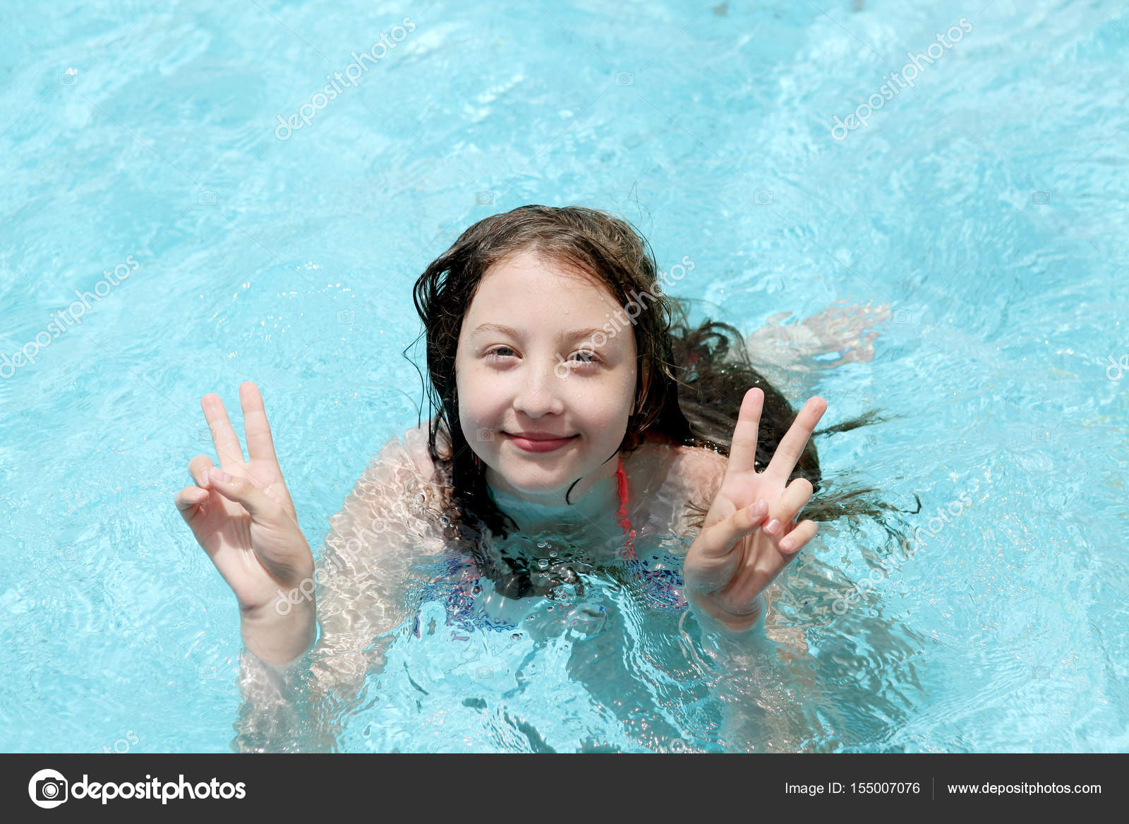 Красивая 13-летняя девочка показывает два больших пальца вверх плавает в ба...