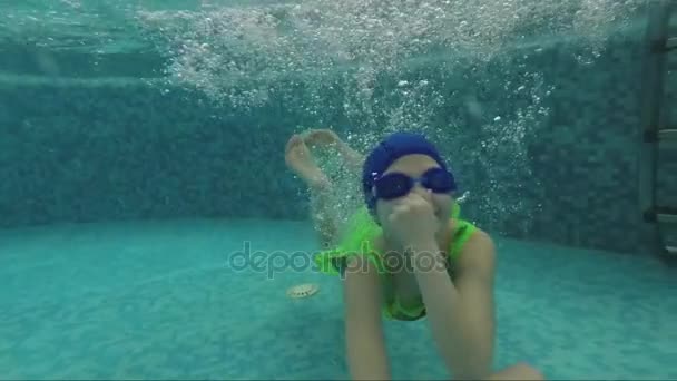Радостный ребенок плавает в бассейне под водой, зажимая нос рукой. Медленное движение — стоковое видео