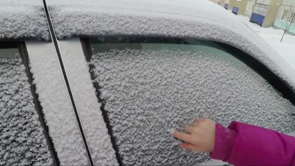 A childs hand paints a heart on a winter car glass — Stock Video