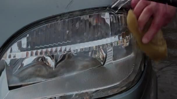 Osoby ruku myje houbičkou auta světlometů. 4k — Stock video