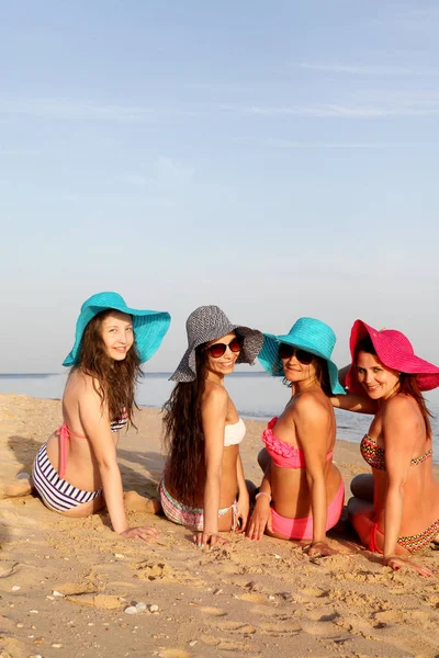Företaget av flickor i badkläder på stranden — Stockfoto