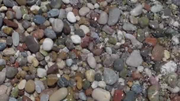 Круглая галька на пляже и прозрачная волна — стоковое видео