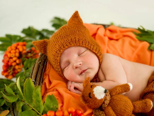 Newborn baby in an orange knitted suit — Stock Photo, Image