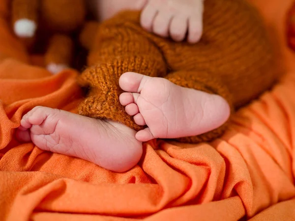 Tender baby legs on an orange cloth. — Stock Photo, Image