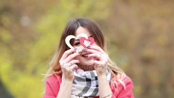 Κορίτσι και δύο ξύλινες καρδιές στα χέρια σε ένα Φθινοπωρινό πάρκο — Αρχείο Βίντεο