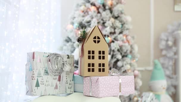 Много новогодних подарков и картонный дом на новогоднем фоне в помещении — стоковое видео