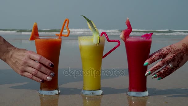Trzy szklanki świeżo wyciśniętego soku na brzegu Oceanu Indyjskiego. 4k — Wideo stockowe