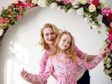 Genç anne ve kucaklama arka planını çiçekler ile bir kemer üzerinde güzel kızıl saçlı kız