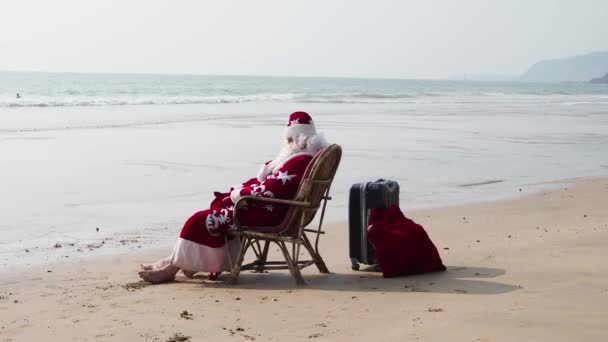 Święty Mikołaj spoczywający na brzegu morza i patrząc w oddali — Wideo stockowe