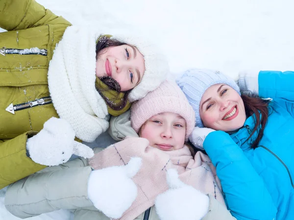 Drie mooie lachende meisjes liggen in de sneeuw — Stockfoto