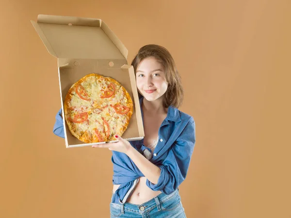 Красива молода дівчина тримає коробку піци на коричневому фоні — стокове фото