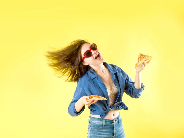 Молода красива жінка їсть шматочок піци пепероні, відкриваючи рот на жовтому фоні — стокове фото