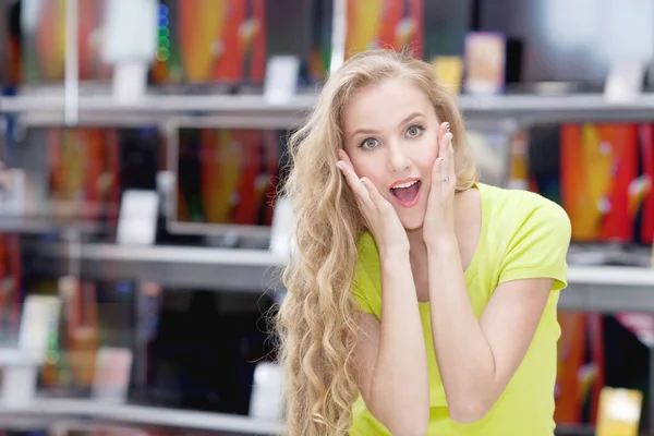 Hermosa chica en una tienda de computadoras mira con sorpresa a la cámara —  Fotos de Stock
