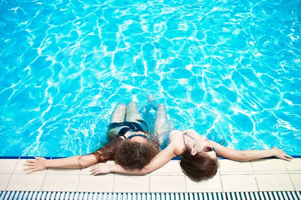 Две молодые женщины наслаждаются бассейном. Курорт, спа, загар — стоковое фото