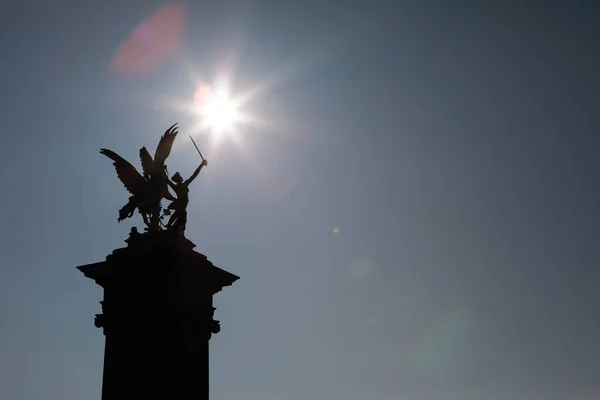 Gökyüzüne karşı bir heykelin karanlık silüeti.