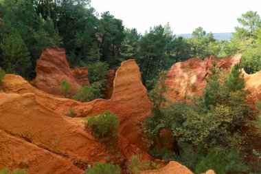 Roussillon 'daki Ochre Patikası, Sentier des Ocres, Güney Fransa' nın Provence kentindeki yeşil ormanlarla çevrili kullanılmayan, kırmızı ve sarı uçurumların doğal renkli bir bölgesinde yürüyüş yolu.