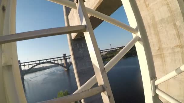 O homem sobe escadas guindaste alto no céu. FPV dispara na câmera gopro. Rufe perigoso, bela vista da cidade e do rio. Construção de pontes . — Vídeo de Stock