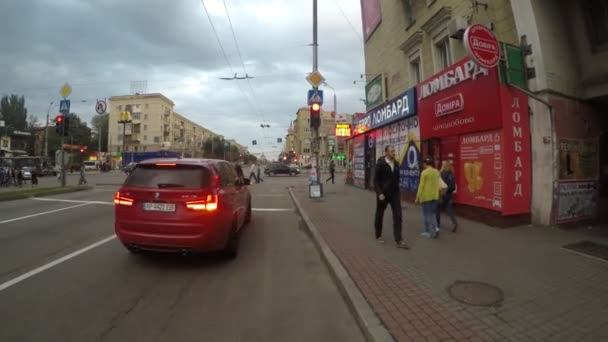 UKRAINE, ZAPOROZHYE, 24 EYLÜL 2017. Bir adam şehrin akşam caddesinde uzun bir tahtanın üzerinde at sürüyor. FPV.gopro. Arabalar arası geçişler, yakınlardan geçen insanlar, trafik ışıkları.. — Stok video