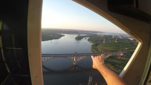 Vue imprenable sur le terrain avec une grue de construction élevée, un homme assis dans un cockpit et regarde la ville, la rivière, les ponts et les voitures, pointant sa main vers l'avant, tirant sur le FPV gopro . — Video