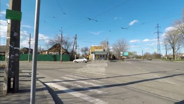 Traffico attraverso un attraversamento pedonale della strada in una chiara giornata di sole con cieli azzurri e nuvole. strada e case vuote . — Video Stock