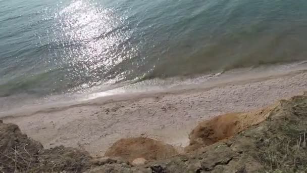 Vue d'en haut de la falaise à la mer et à la plage, lumière vive et petites vagues 