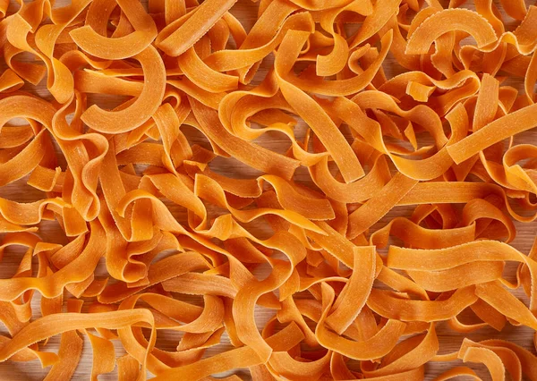 พาสต้าส้ม พาสต้าแห้งกับพื้นหลังมะเขือเทศ — ภาพถ่ายสต็อก