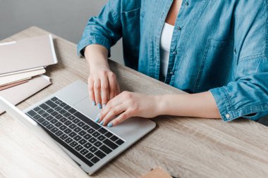 cropped view of woman working with laptop in office clipart