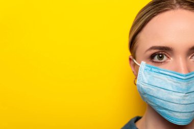 cropped view of young woman in medical mask on yellow background, coronavirus concept clipart