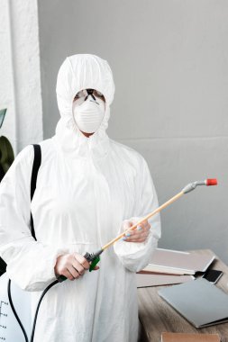 Beyaz tehlikeli madde giysisi, solunum cihazı ve gözlük takan kişi işyerinde dezenfekte etme, koronavirüs konsepti