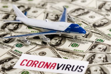 Coronavirus kartının seçici odak noktası ve dolar banknotları üzerine uçak modeli, ekonomik kriz kavramı