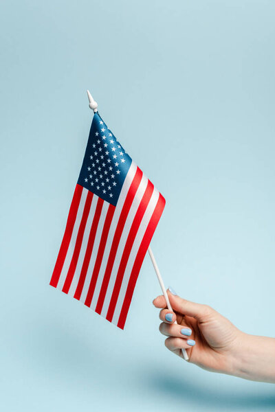 cropped view of woman holding american flag on blue background, coronavirus concept