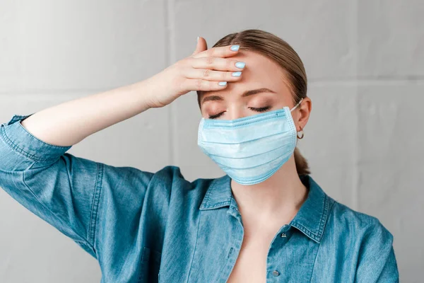 Frau Medizinischer Maske Berührt Stirn Mit Geschlossenen Augen — kostenloses Stockfoto