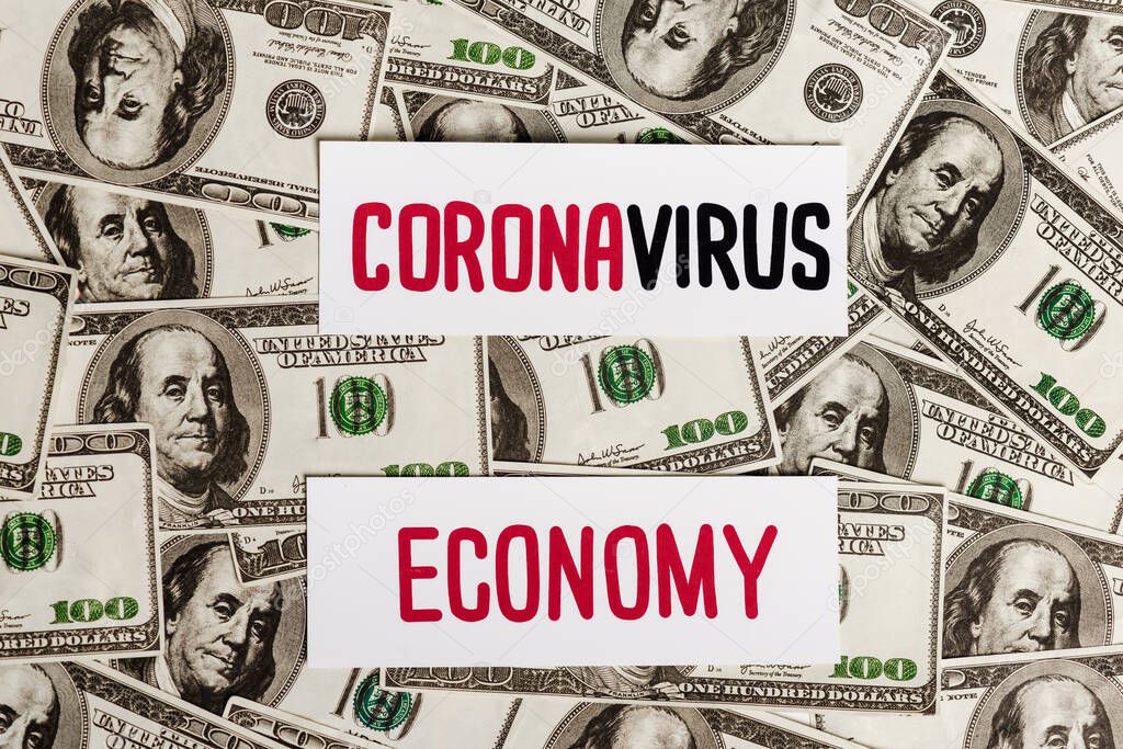 top view of coronavirus and economy cards on dollar banknotes, economic crisis concept